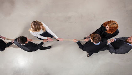 rival business man and woman compete for the command by pulling the rope