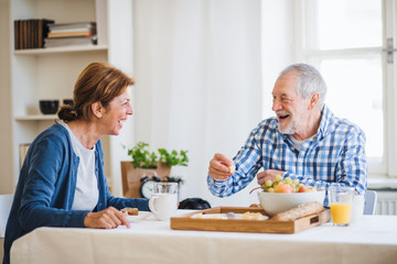 Sticker - A senior couple sitting at the table at home, having breakfast.