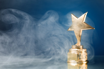 Wall Mural - gold star trophy in smoke, blue background
