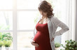© StockPhotoPro - Young mother posing next to a window