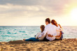 © karelnoppe - Young family sitting together in late afternoon sun on beach.