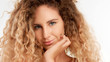 © Anastasia - closeup portraitof green eyed model with big curly blonde hair, ideal skin with chin on hand watching to the camera smiling slightly