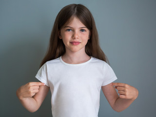 portrait of a beautiful young girl in a white t-shirt on a gray background, concept advertising