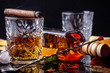 concept of alcoholism, loneliness, dependence. A bottle of whiskey, a glass of whiskey and with ice, a cigar with smoke on a black table, on a black background. Elite drink for masculine relaxation