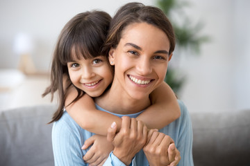 beautiful family of single young mom and cute preschool kid daughter embracing mommy looking at came