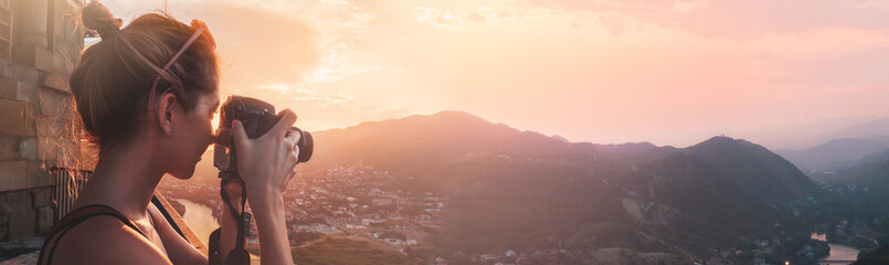 female photographer, taking pictures of mountain landscape at sunset, long panoramic