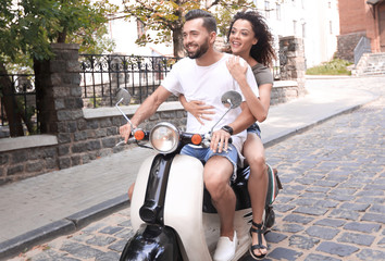 Canvas Print - Cheerful young couple riding a scooter and having fun