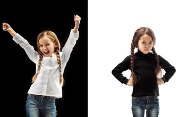 The portrait of emotional happy winner girl and serious girl on a white and black studio background. Human emotions concept. Comparison of different emotions. The childhood, kid, friendship concept