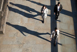 Fototapeta Londyn - Aerial view of three city workers walking on a sunny urban street, horizontal