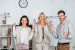 © LIGHTFIELD STUDIOS - happy professional business colleagues triumphing and smiling at camera in office