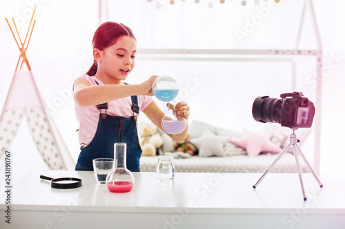 Fotografia, Obraz Dark-haired blogger filming video about chemistry in her living room