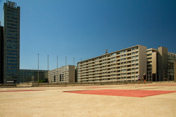 Architectural generic 1950s concrete facades in low landscape perspective of buildings exterior and paving in red colour with a blue sky background in Vienna Austria