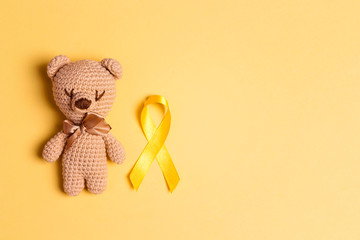 Wall Mural - Children's toy with a Childhood Cancer Awareness Yellow Ribbon on yellow background.