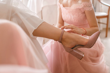 Wall Mural - A girlfriend helps a bride to put on her wedding shoes. Beautiful female feet closeup