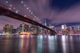 Fototapeta  - View on Financial district with Brooklyn bridge from east river at night with long exposure