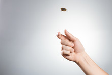 Hand Throwing Up A Coin On Gray Background