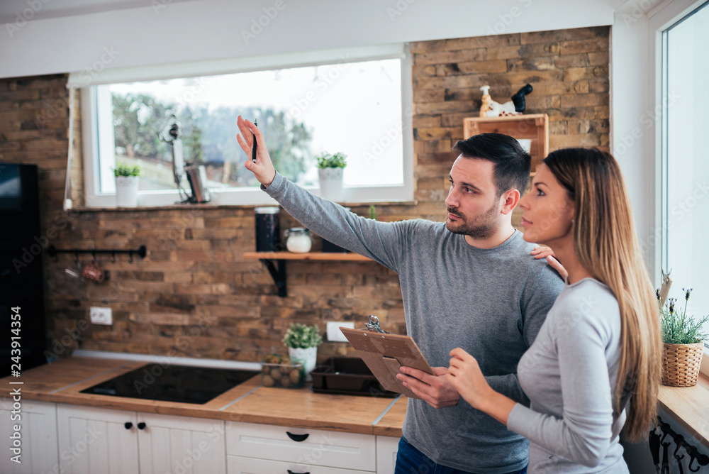 Couple talking about home renovation. Standing in the kitchen and discussing apartment renovation ideas. - obrazy, fototapety, plakaty 