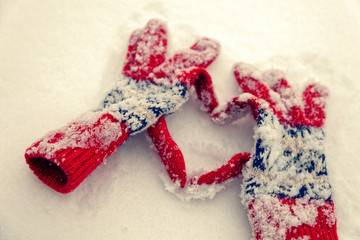 Winter gloves make the shape of a heart on a snow.