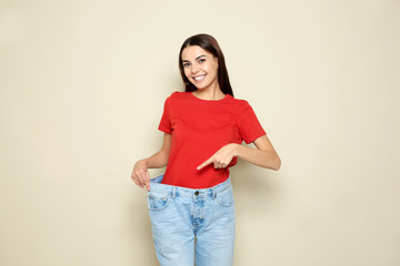 Wall Mural - Slim woman in oversized jeans on color background. Weight loss