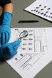 © New Africa - Criminalist exploring fingerprints with magnifying glass at table, closeup