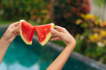 Close up of women's hands make a butterfly shape from two pieces of watermelon