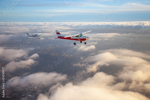 Fotografía Popular single-engine airplane flying through the clouds on a beautiful sunset s