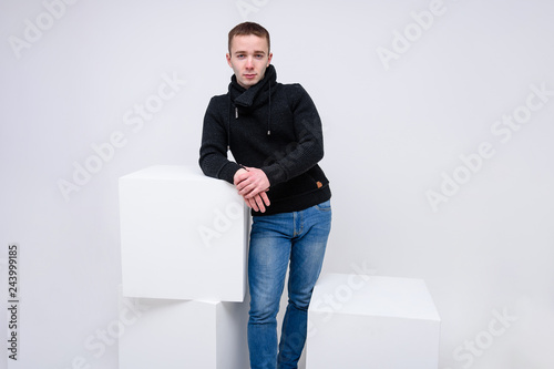 Fotografía Concept studio portrait of a young man on a white background sitting on a cube and talking