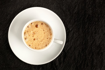 Poster - A cup of regular coffee with foam on a dark black background with a place for text