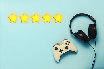 Wall Mural - Gamepad and headphones on a blue background. Added five stars rating. Reputation. The concept of the game on the console, gambling. Flat lay, top view.