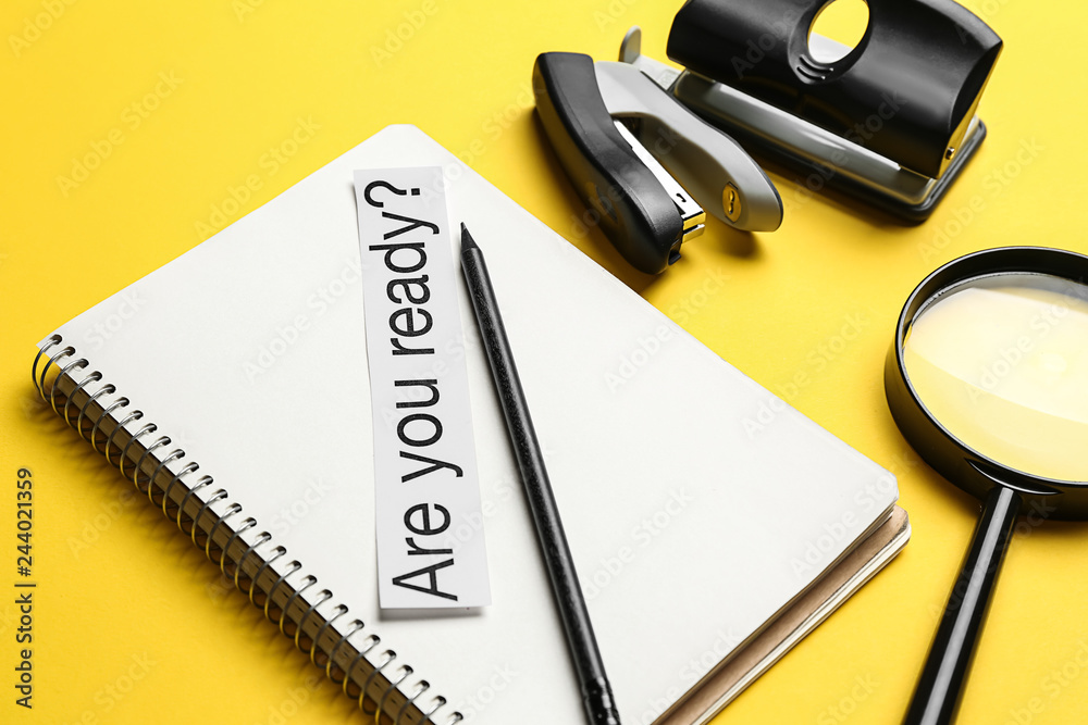 Notebook, stationery and paper with text ARE YOU READY? on color background. Concept of preparation for school test