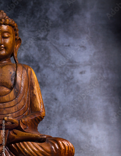 Fotografía Wooden made buddha on a grey stone background