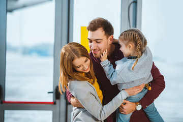 Wall Mural - happy family smiling while hugging in airport