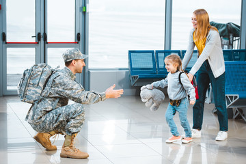 Wall Mural - Cheerful daughter running to happy father in military uniform in airport