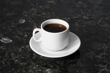 White cup of esoresso on granite table surface