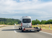 Minibus With Empty Tow Truck Transporter On Highway. Space For Text