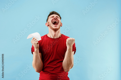 Fotografía Young boy with a surprised happy expression bet slip on blue studio background