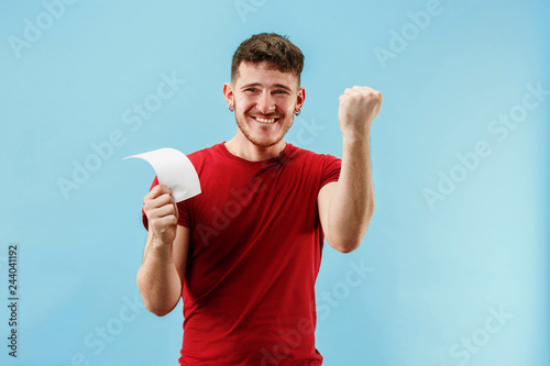 Fotografía Young boy with a surprised happy expression bet slip on blue studio background