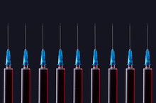 Multiple Syringes Organized In A Pattern Over Dark Background