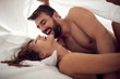 Smiling man and woman making love in bedroom.