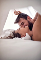 Wall Mural - young man and woman lovers having sex on a bed in morning with lust and love. sex couple. having sex