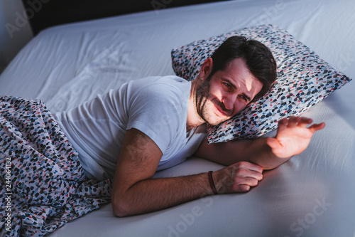 Fotografija Young tired man waking up in bed in the morning