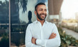 © JonoErasmus - Portrait of a young confident smiling indian man with his arms crossed looking into the distance