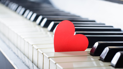 Red bright heart on a keyboard of an old piano. Cocept of love, valentine's day