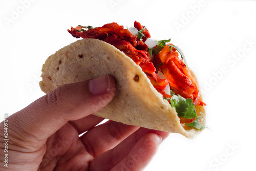 Fotomural Close-up of a hand holding authentic mexican taco al pastor on a white backgroun