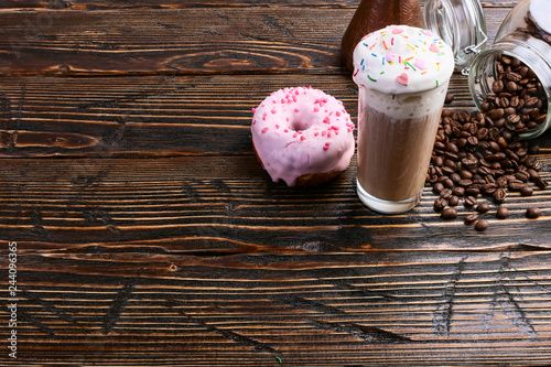 Fotografía A donut with pink icing and chocolate powder and a cappuccino glass with high foam and decoration