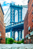 Fototapeta Panele - Manhattan Bridge between Manhattan and Brooklyn over East River seen from a narrow alley enclosed by two brick buildings on a sunny day in Washington street in Dumbo, Brooklyn, NYC