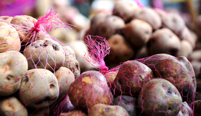Fresh potatoes in pink potatoe net bags at the supermarket
