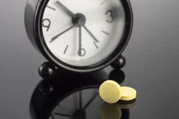 Wall Mural - Yellow pills next to a clock, conceptual image