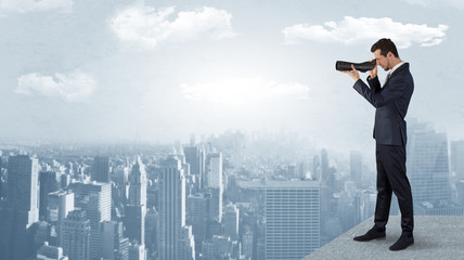 Wall Mural - businessman looking forward to a city with binoculars from skyscraper concept