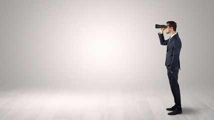 Wall Mural - businessman looking forward with binoculars in an empty space